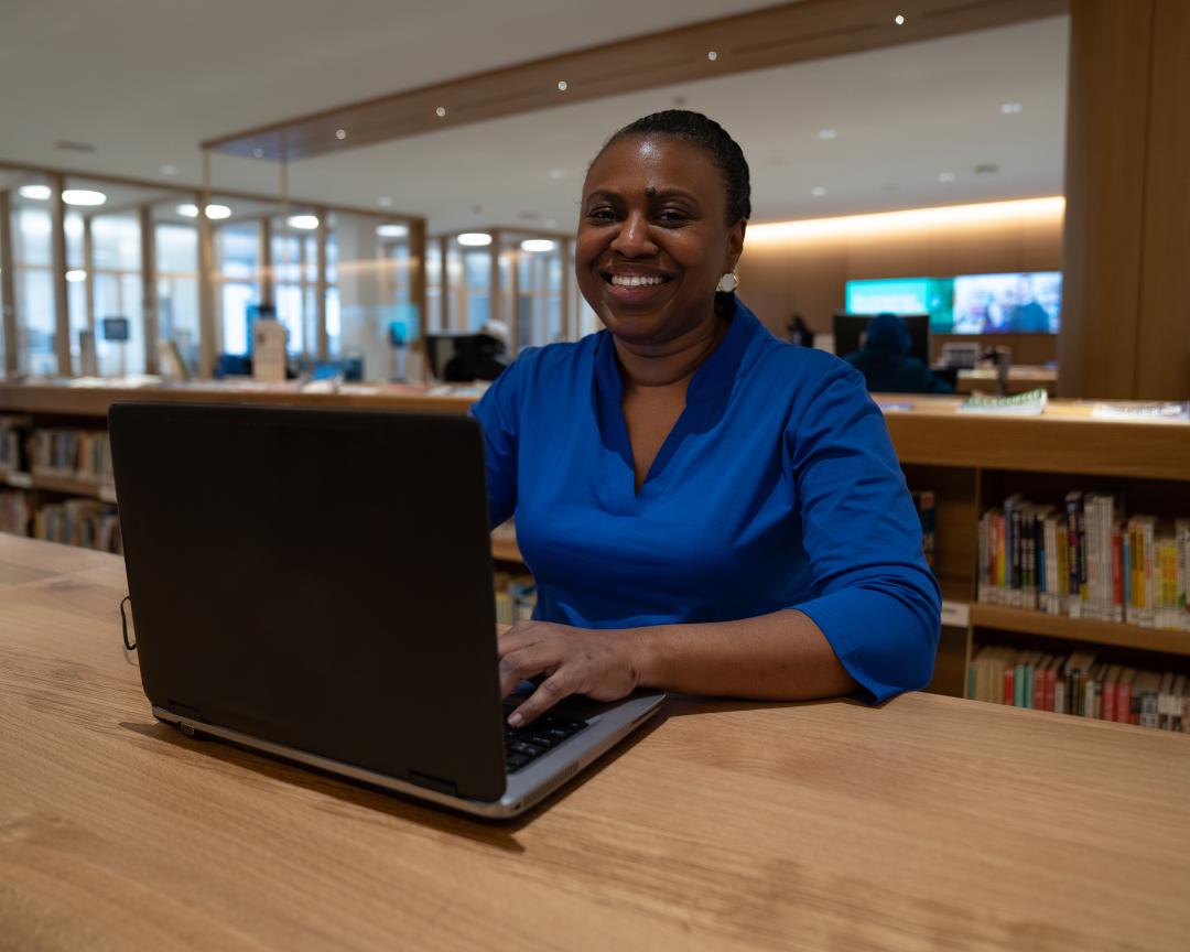 Tasha Taylor sitting in a library in front of a laptop.